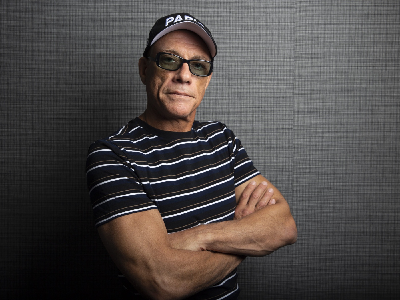 Популярный актер Жан-Клод Ван Дамм в кепке у стены