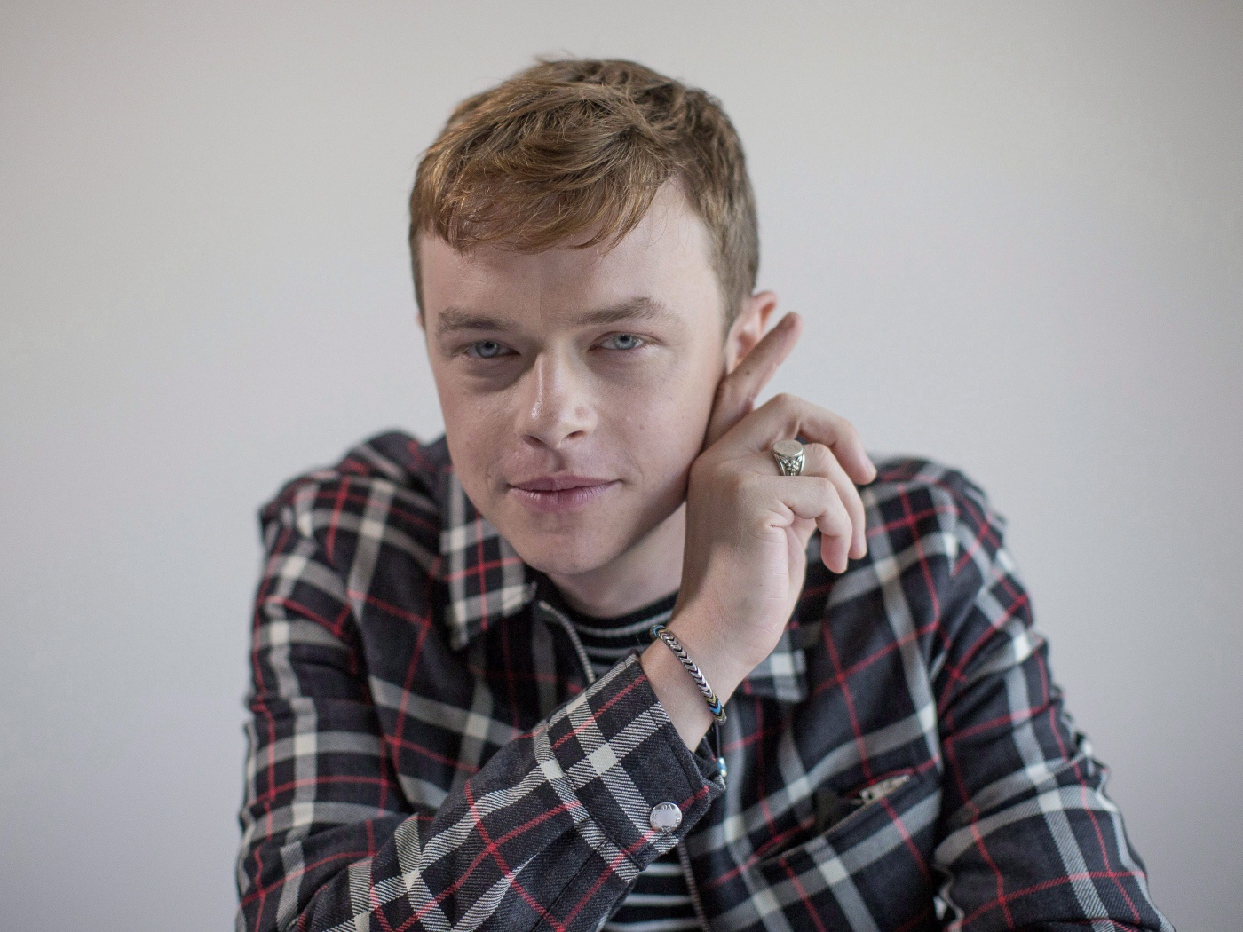 Молодой актер Дэйн Дехаан в рубашке на сером фоне