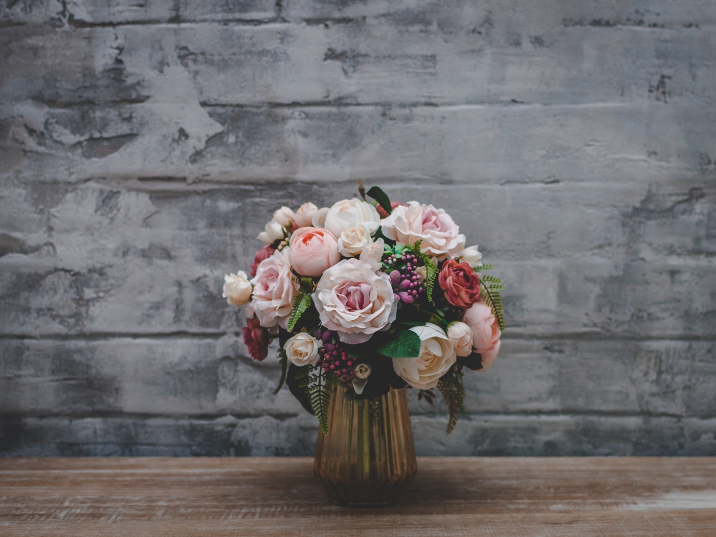 Розовый букет роз  стоит у серой стены 