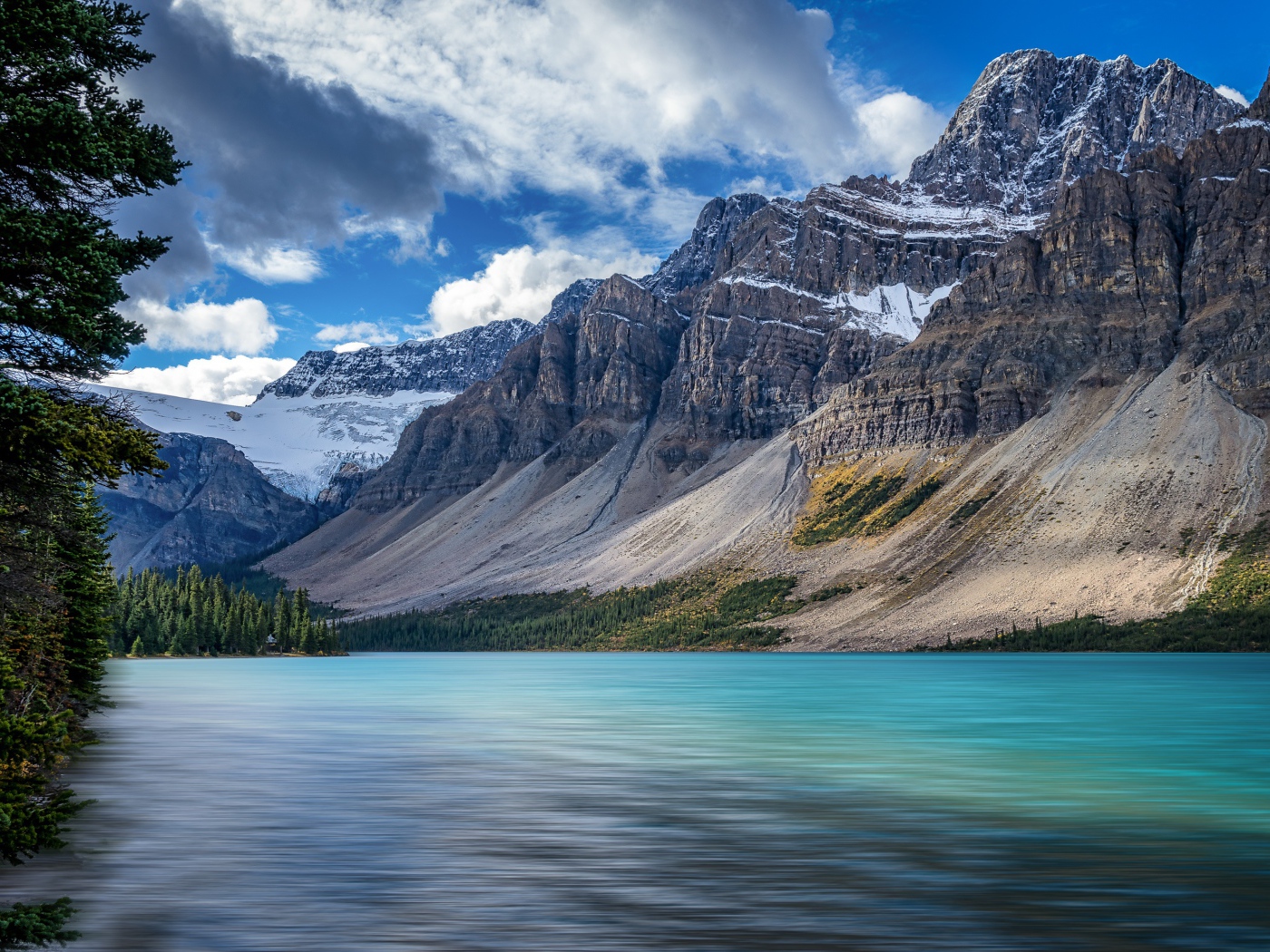 Высокие каменные горы в снегу под голубым небом у озера 