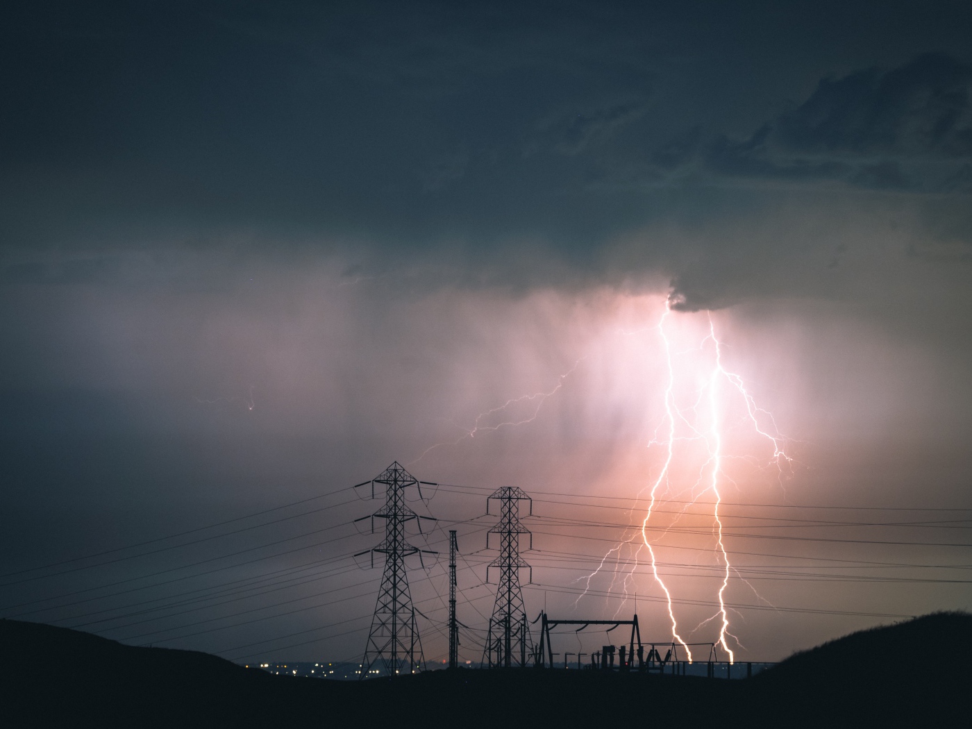 Яркая молния в небе над высоковольтной линией 