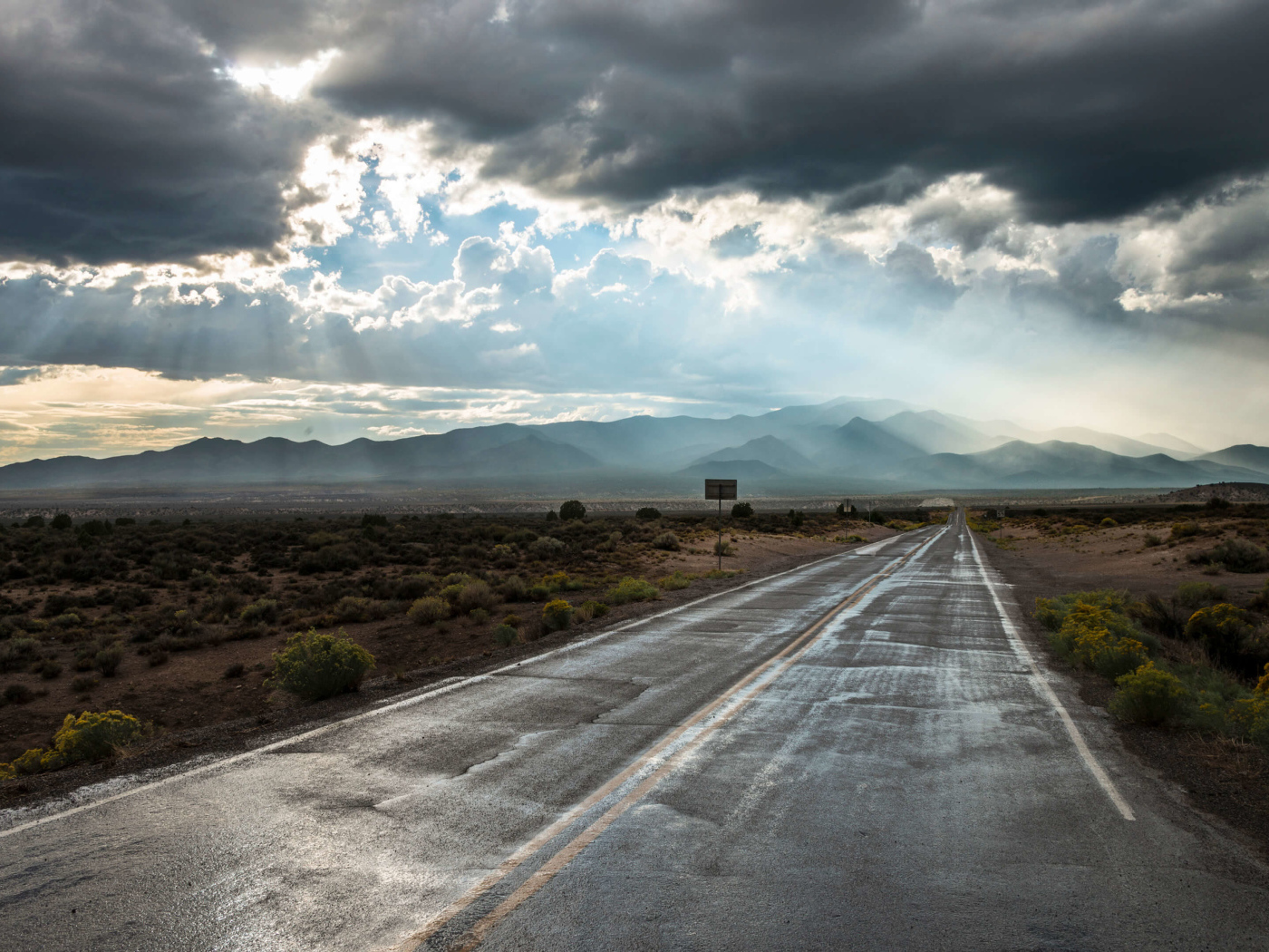 Мокрая дорога в лучах солнца под пасмурным небом 