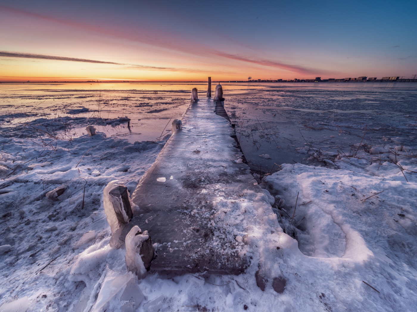 Покрытый льдом деревянный мост у озера 