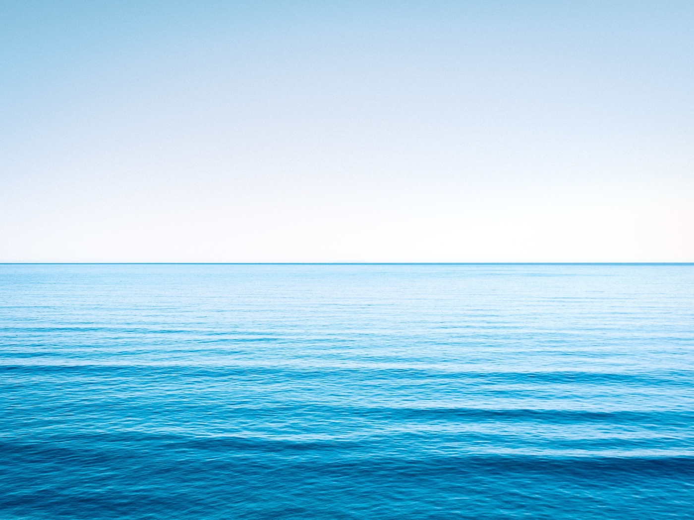 Спокойная голубая морская вода под голубым небом 