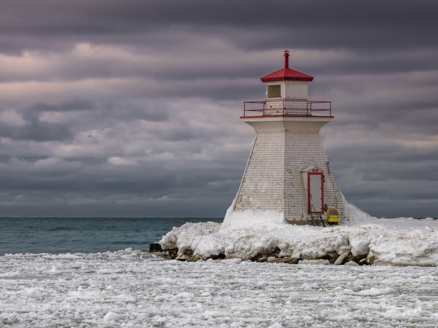 Маяк на покрытом льдом берегу у моря