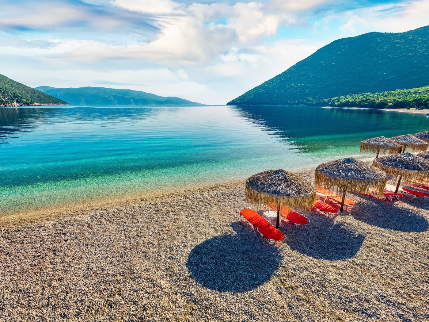 Шезлонги стоят на берегу озера у гор 