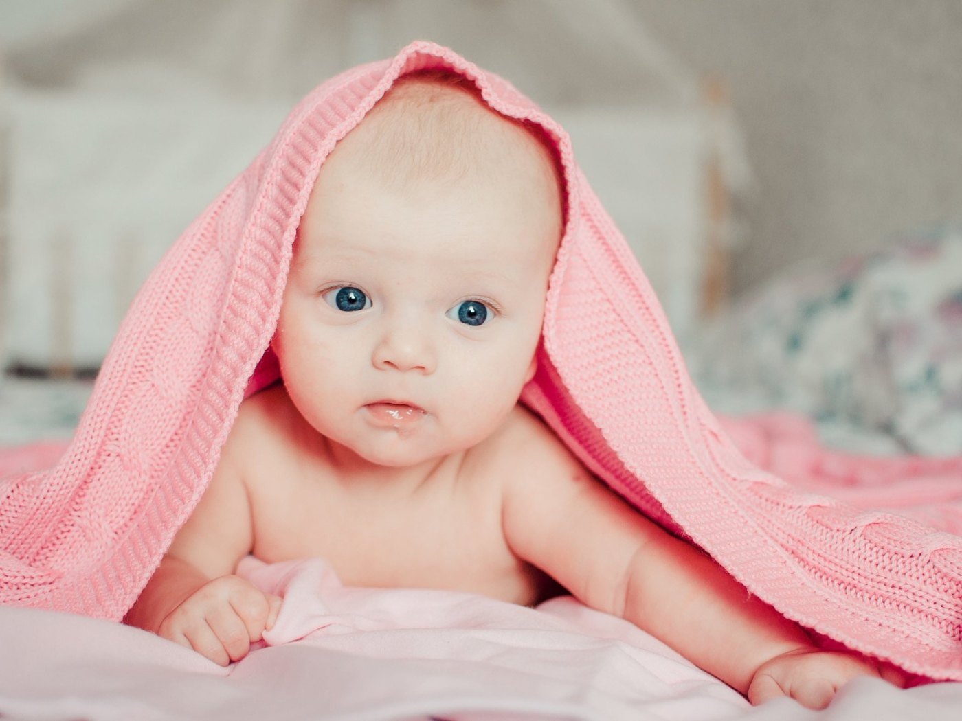 Грудной ребенок лежит под розовым пледом