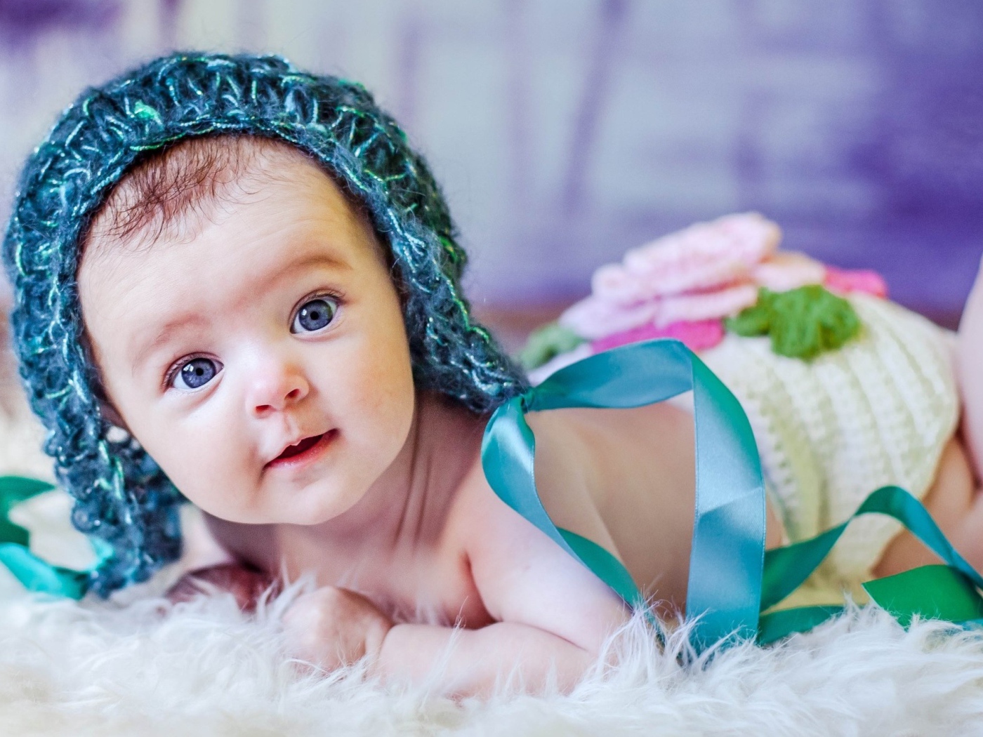 Голубоглазая маленькая девочка в вязаной шапке с ленточками