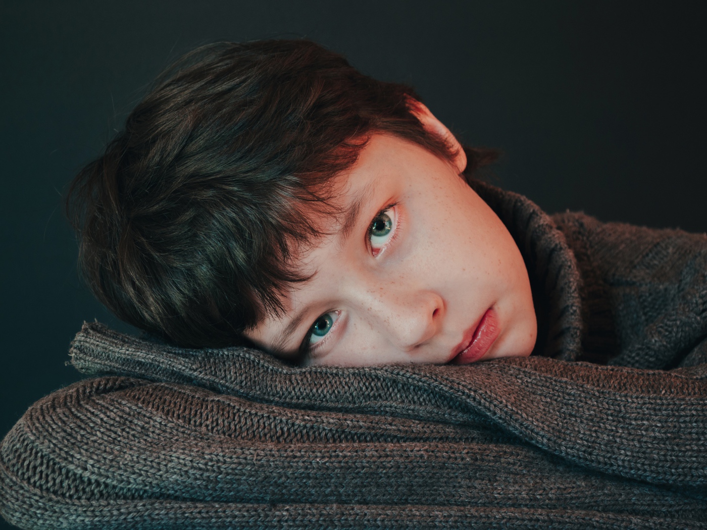 Мальчик в теплом свитере на сером фоне 