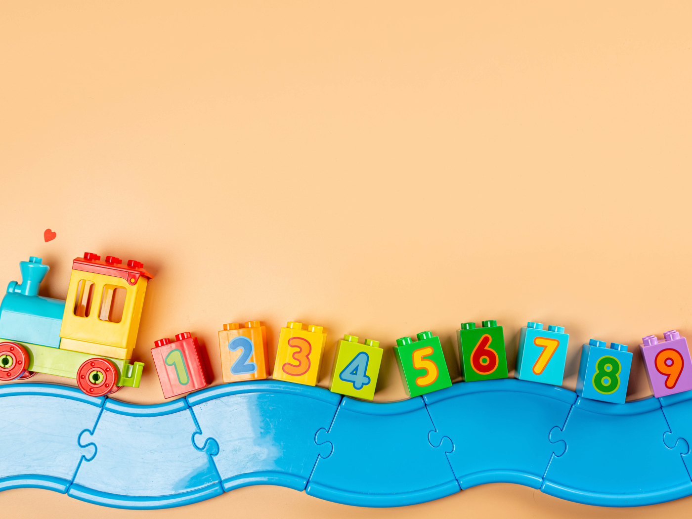 Детский игрушечный паровоз на бежевом фоне 