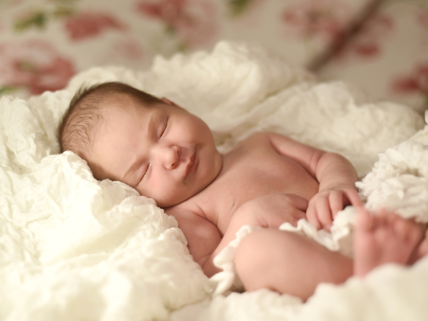 Милый грудной ребенок спит на белом покрывале 