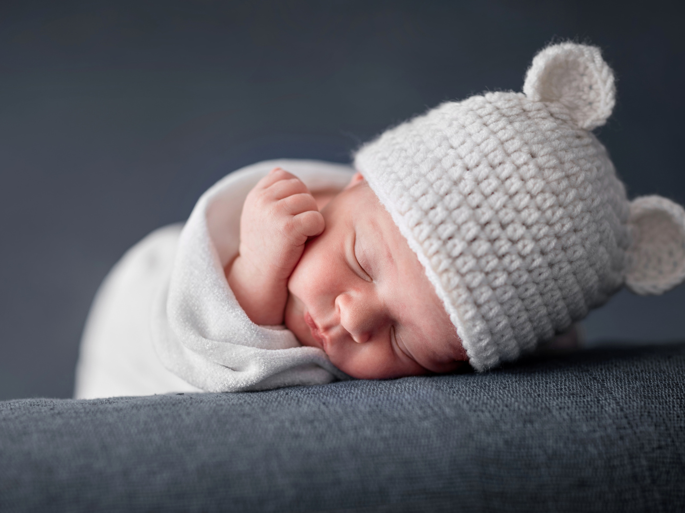 Милый спящий ребенок в белой шапке с ушками