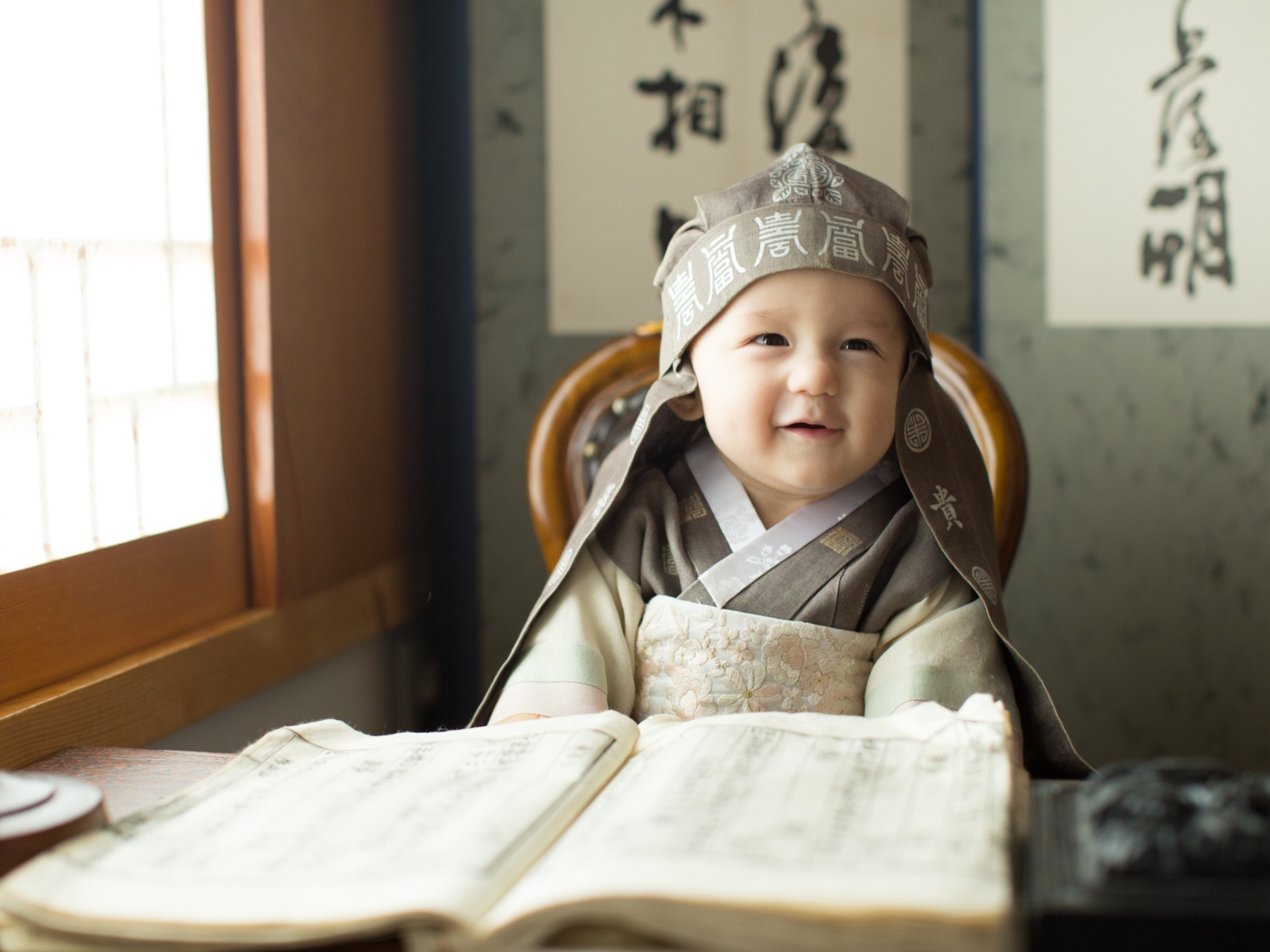 Маленький азиатский мальчик за столом с книгой