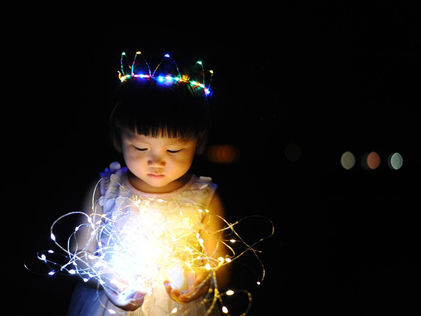 Маленькая девочка азиатка с гирляндой в руках на черном фоне