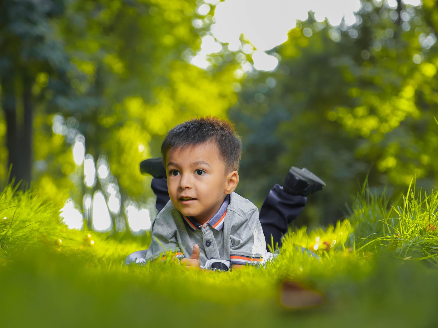 Маленький мальчик лежит на зеленой траве 