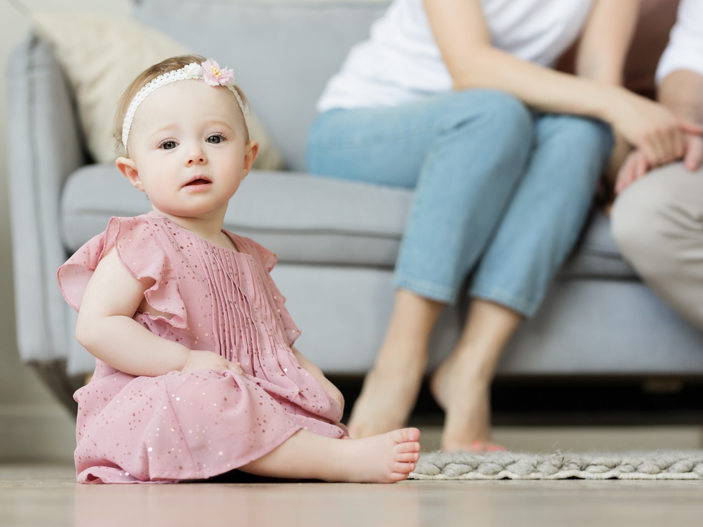 Маленькая девочка в розовом платье сидит на полу