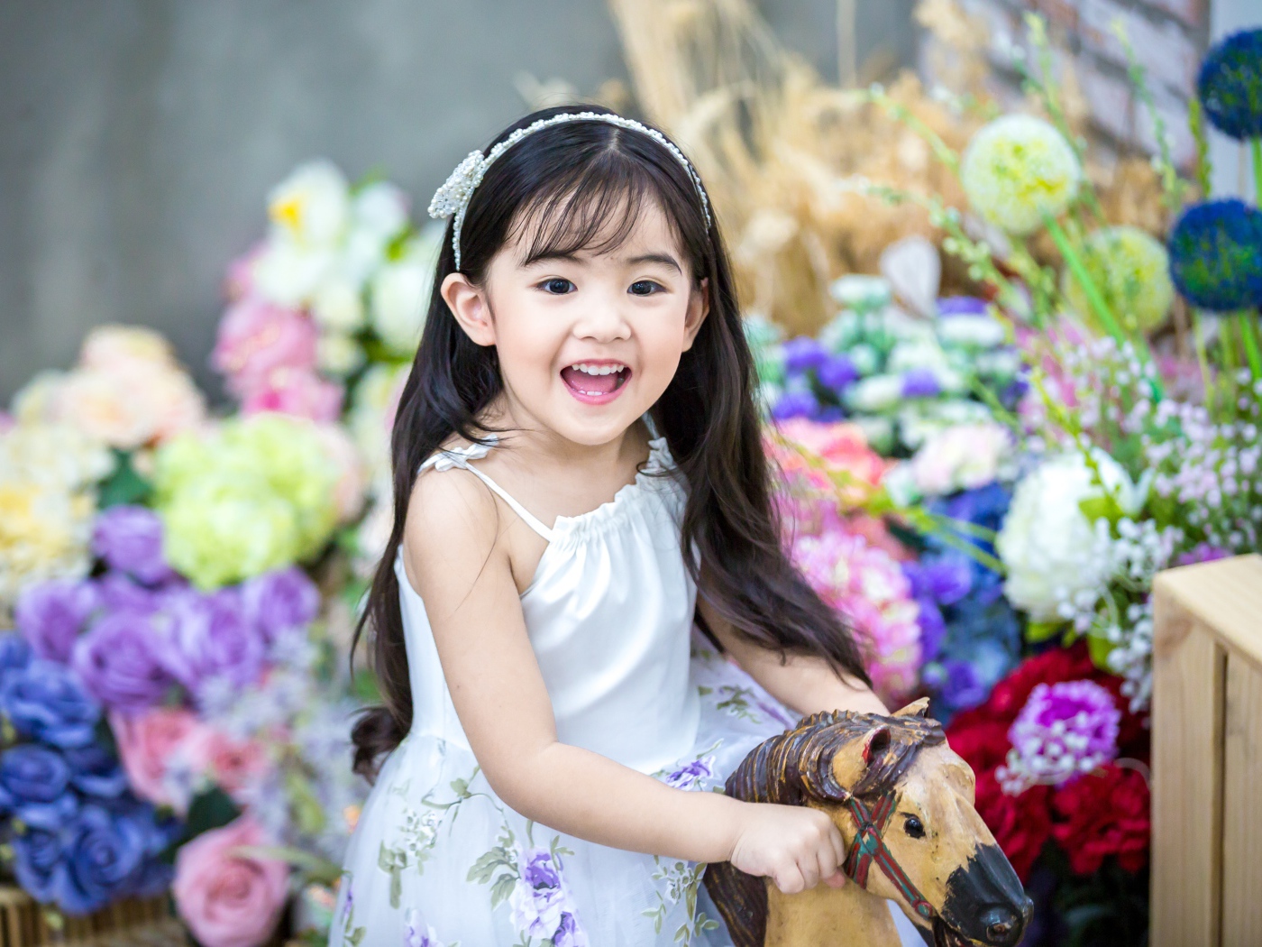 Smiling little asian girl riding a horse