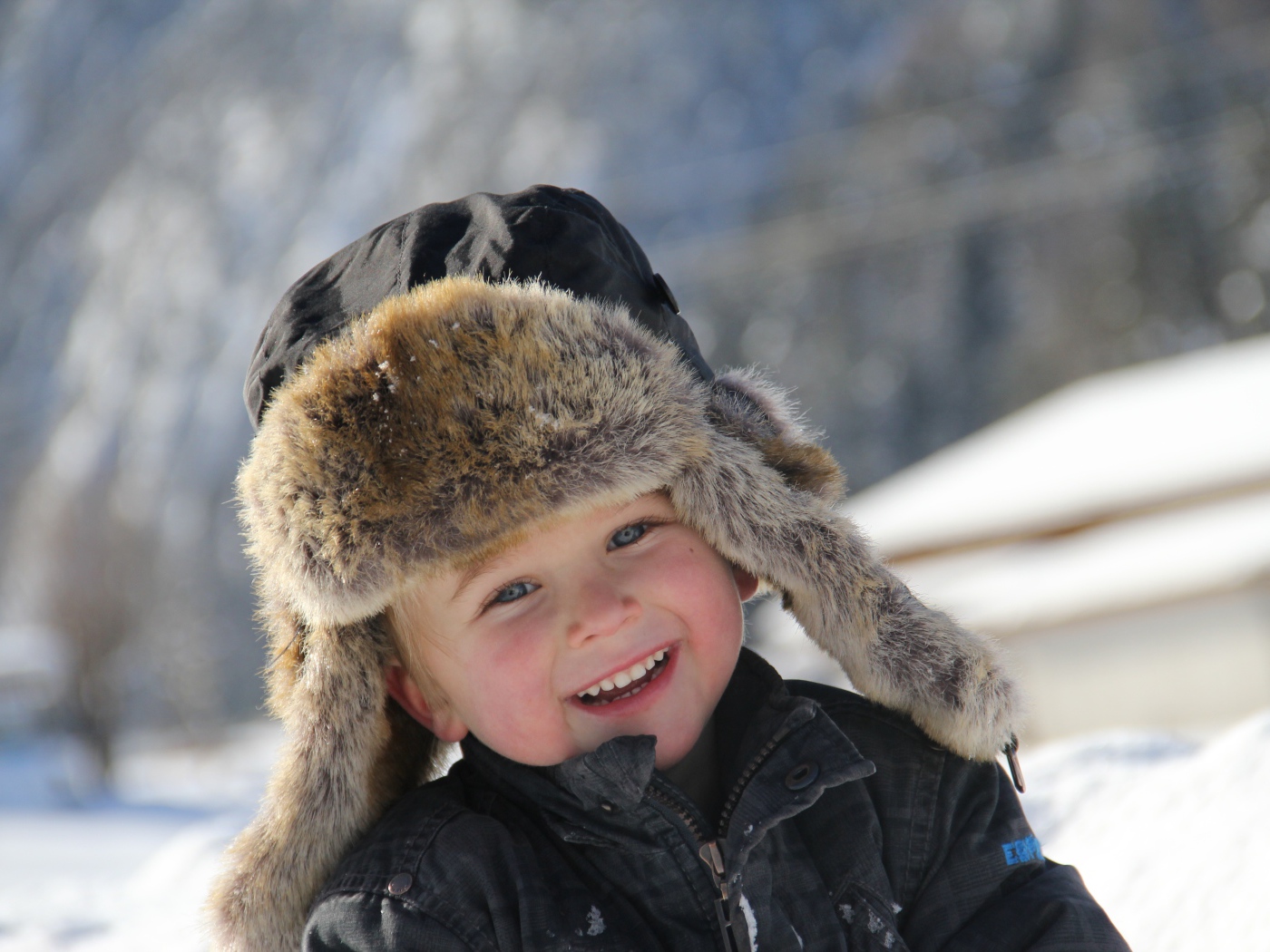 Улыбающийся  маленький мальчик в зимней шапке 