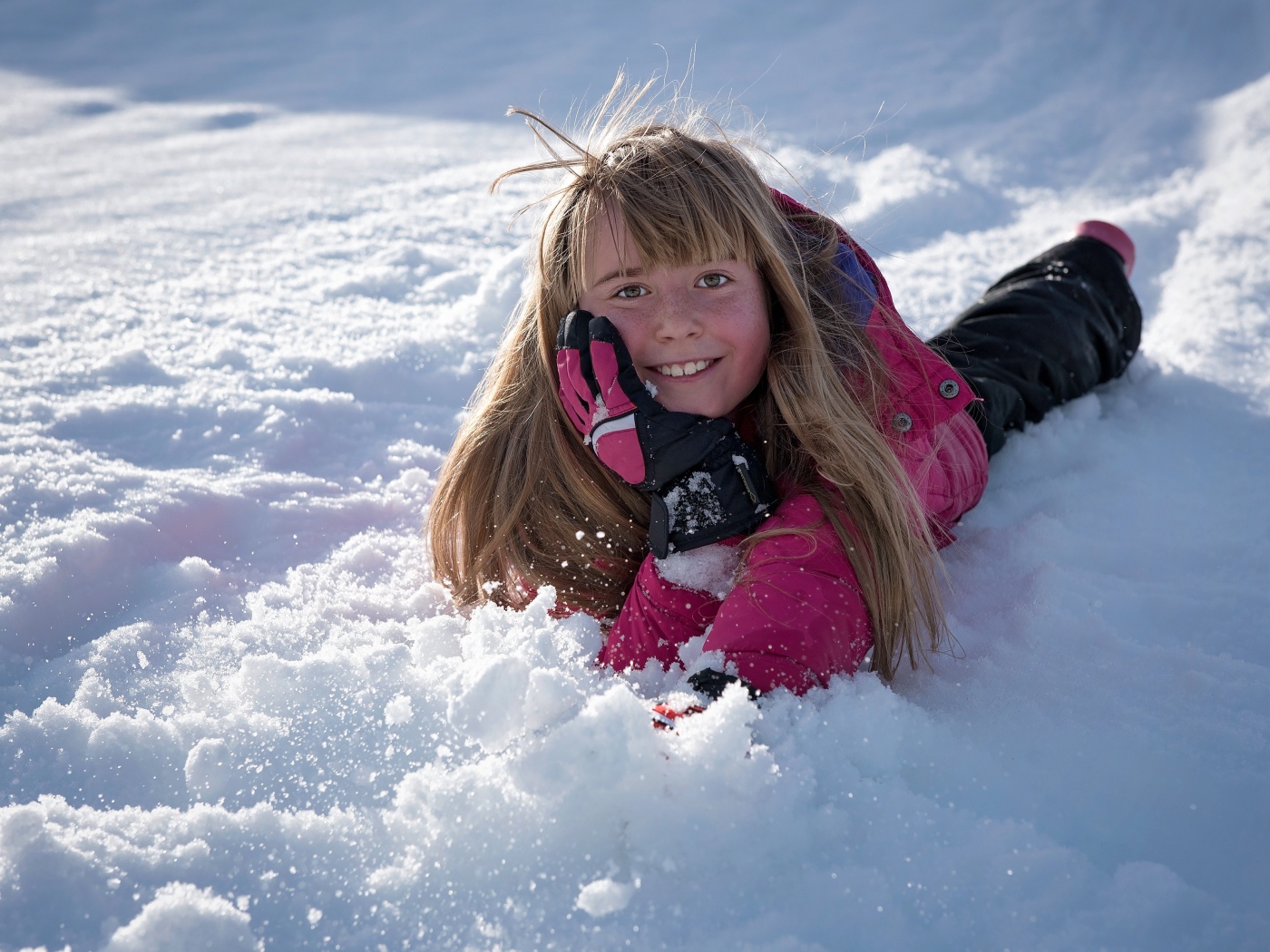 Улыбающаяся маленькая девочка лежит на снегу