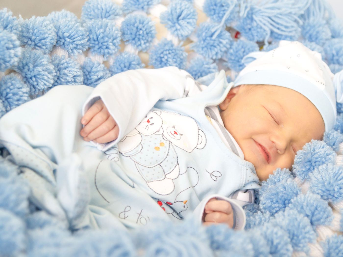 Улыбающийся грудной ребенок спит на голубом покрывале