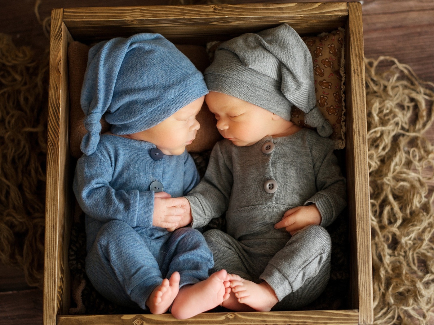 Два маленьких грудных ребенка спят в деревянном ящике