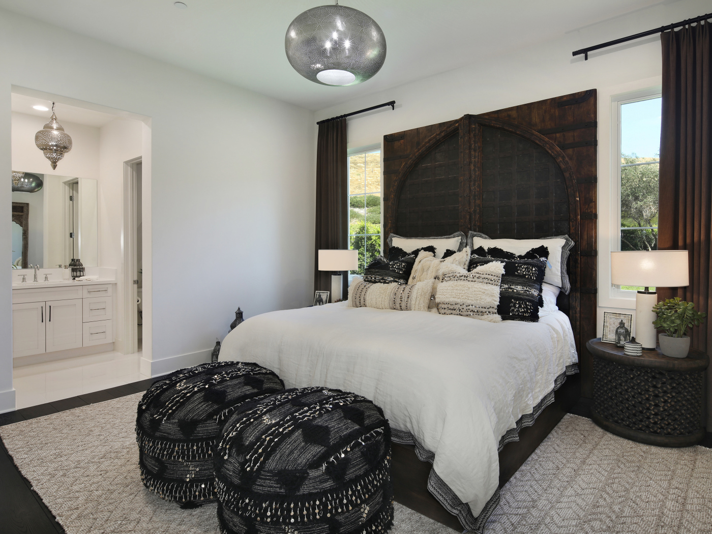 Большая кровать в спальне с большими окнами со шторами