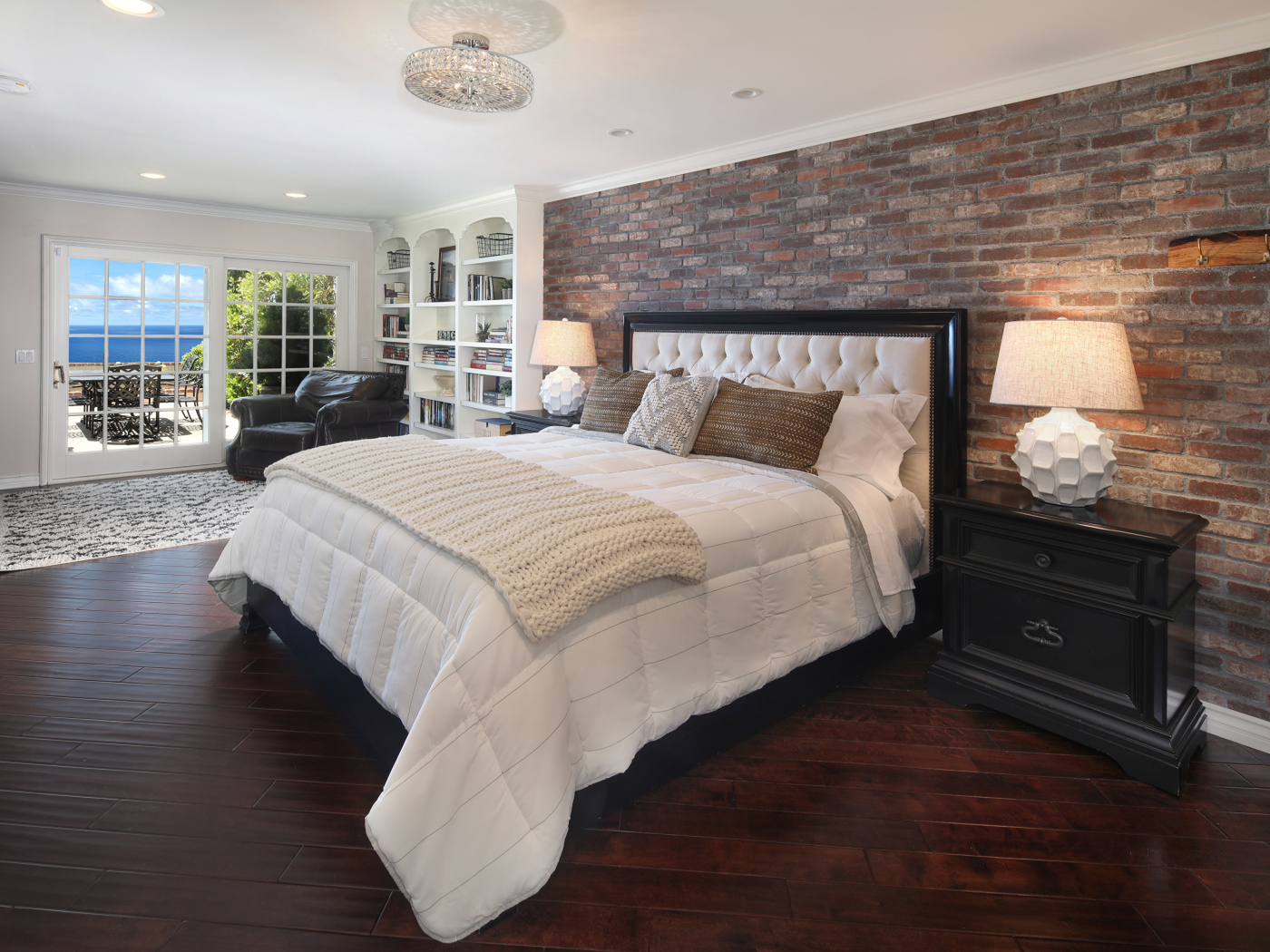 Большая кровать с белым покрывалом в спальне у окна