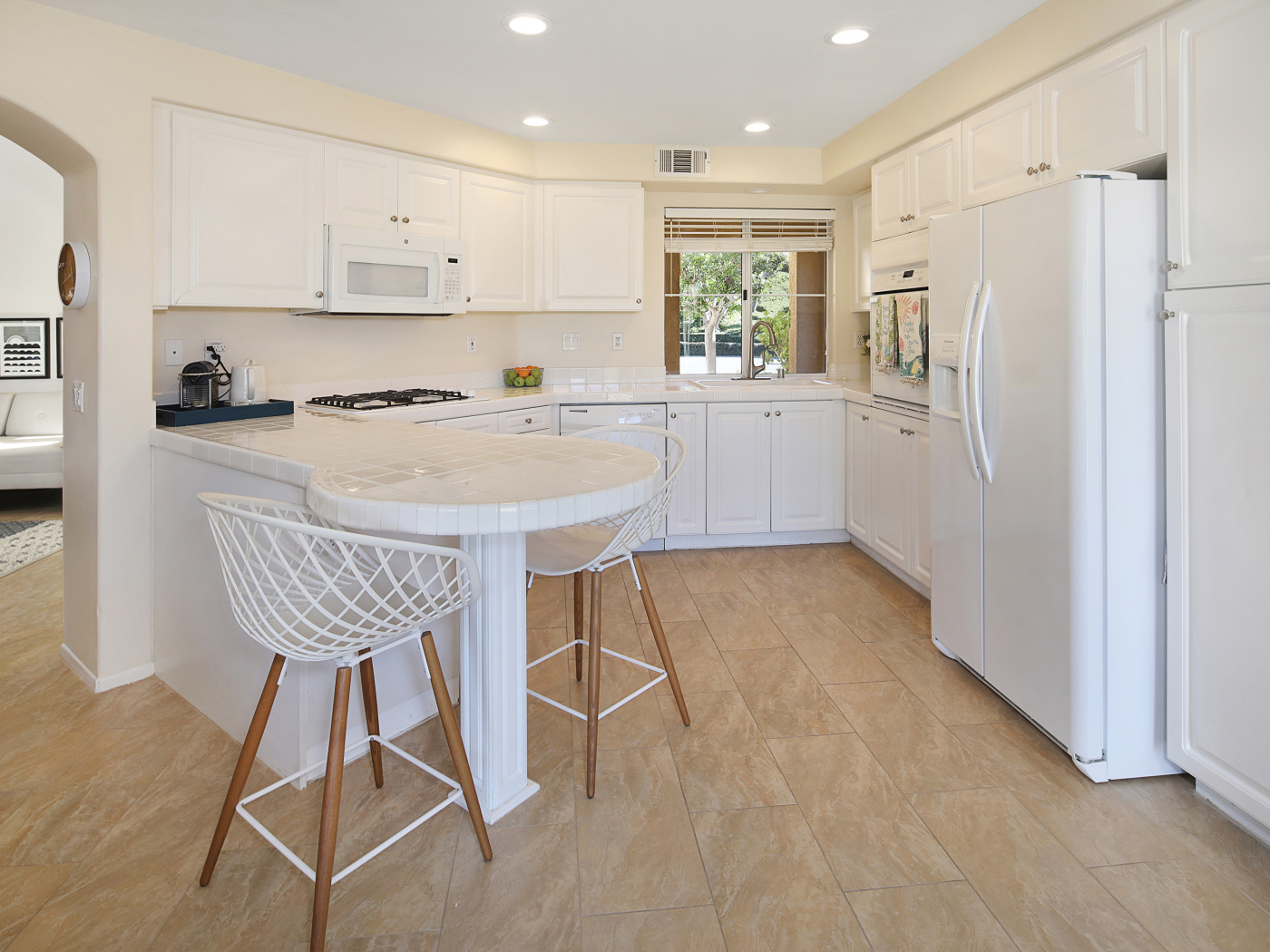 Большой холодильник и белая мебель на кухне 