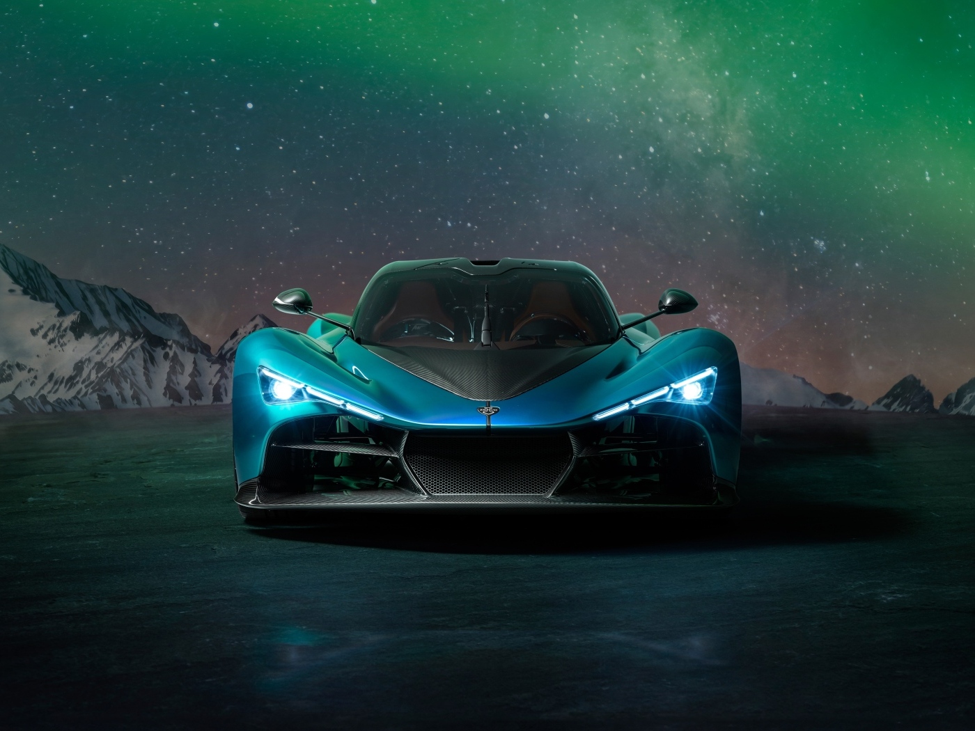 Голубой спортивный автомобиль Zenvo Aurora на фоне гор и полярного сияния
