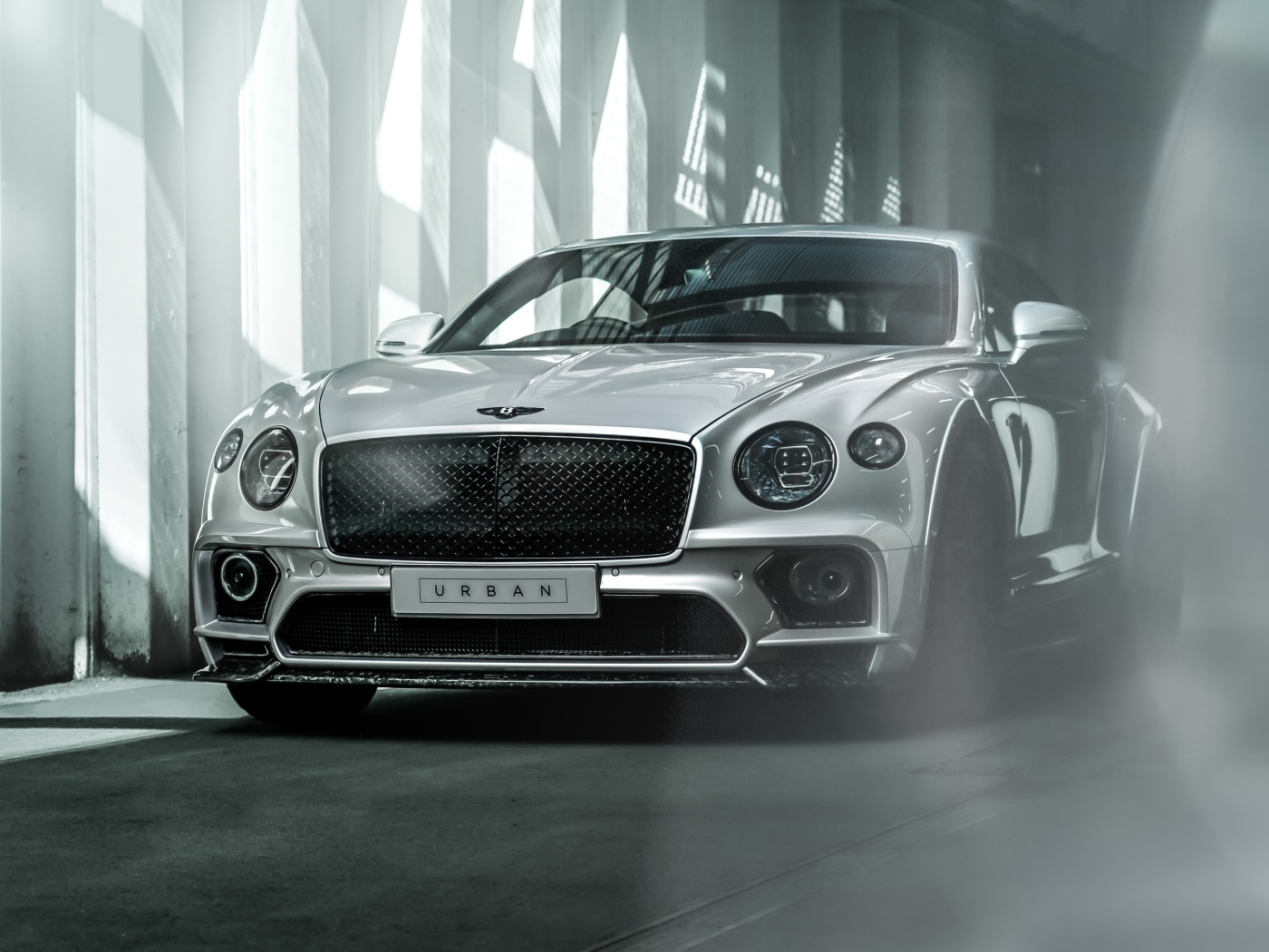 Серебристый автомобиль Bentley Continental GT в здании