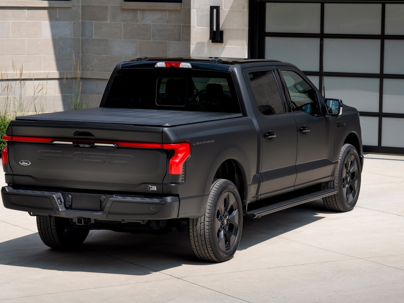 Черный пикап Ford F-150, 2024 года стоит у гаража