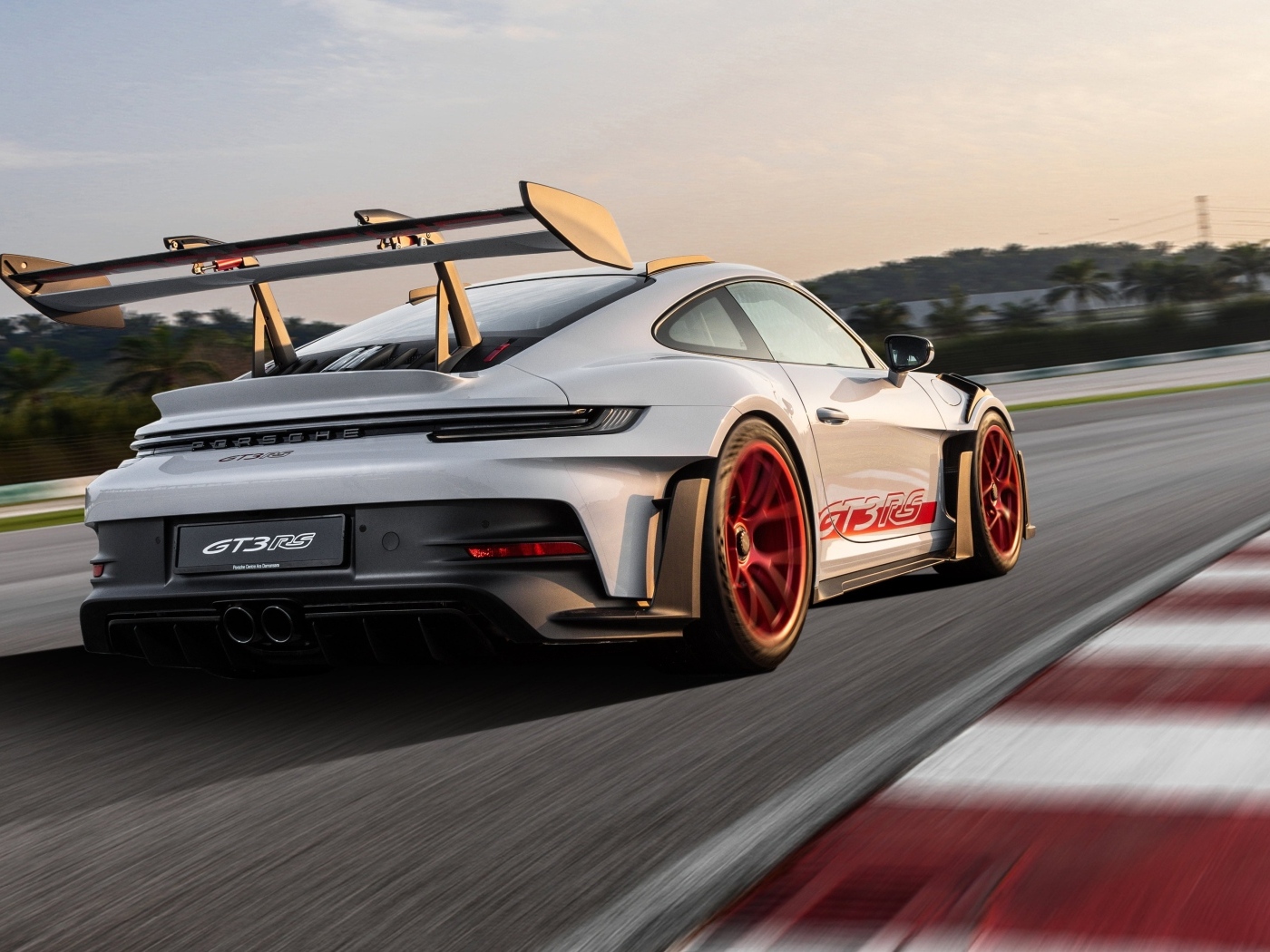 Серебристый спортивный автомобиль Porsche 911 GT3 RS Weissach Package 2023 года на трассе
