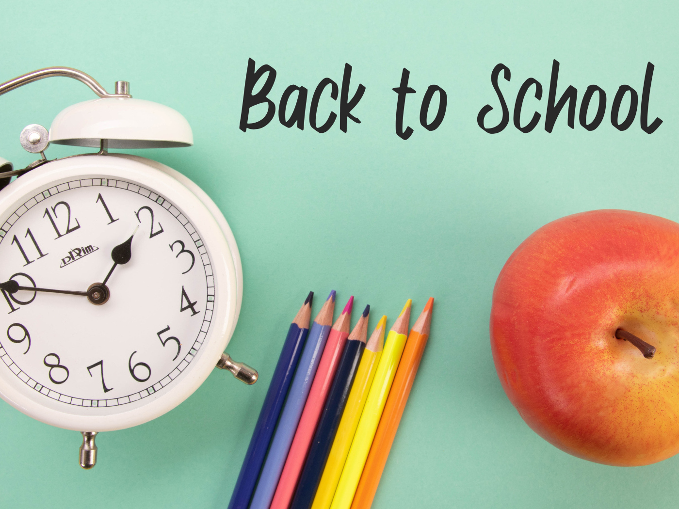 Цветные карандаши на голубом фоне с часами и яблоком