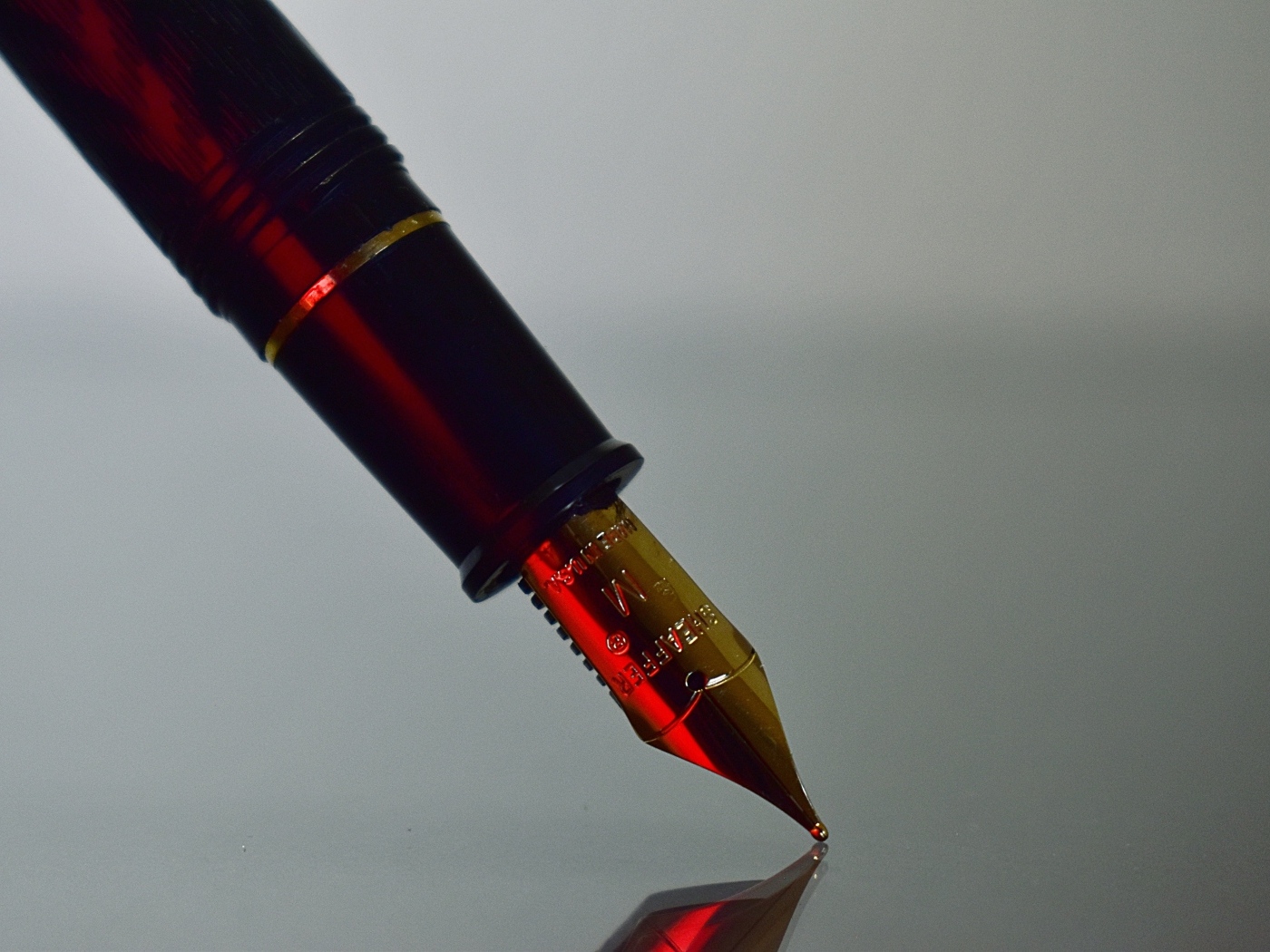 Золотое перо чернильной ручки на сером фоне