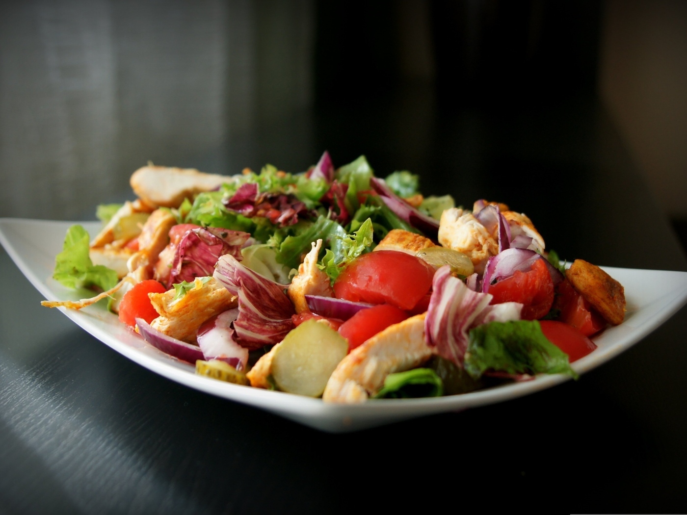 Аппетитный салат в белой тарелке на черном фоне