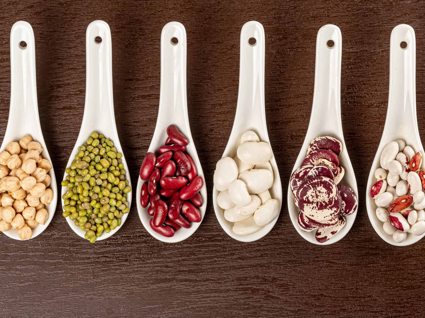 Бобовые зерна в белых ложках на столе