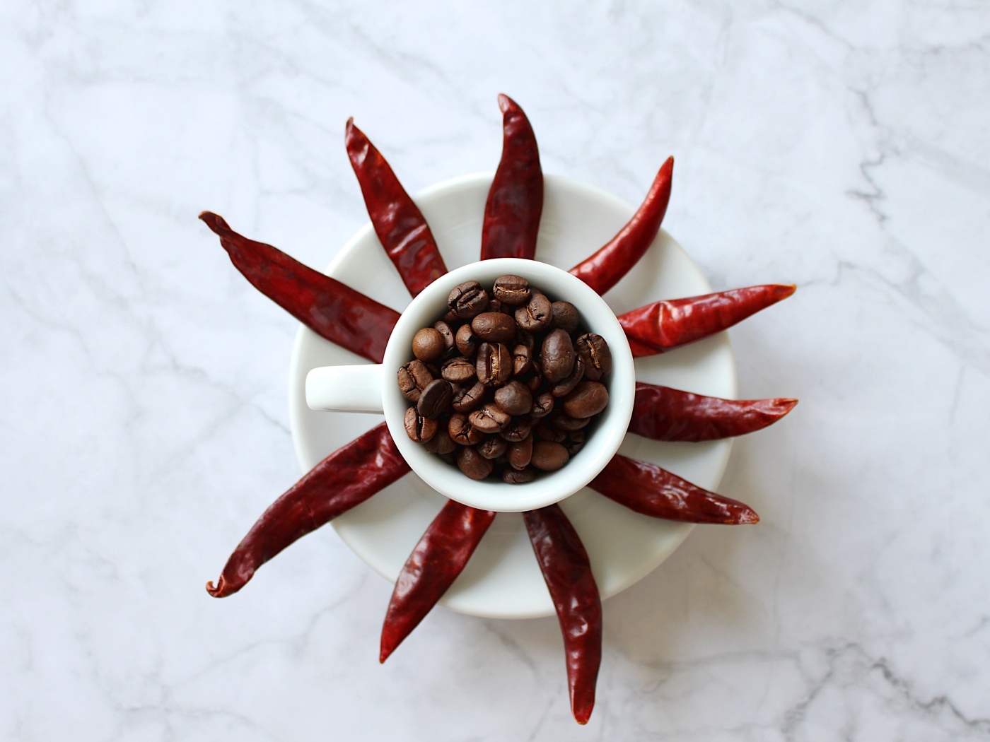 Кофейные зерна в чашке на тарелке с красным перцем