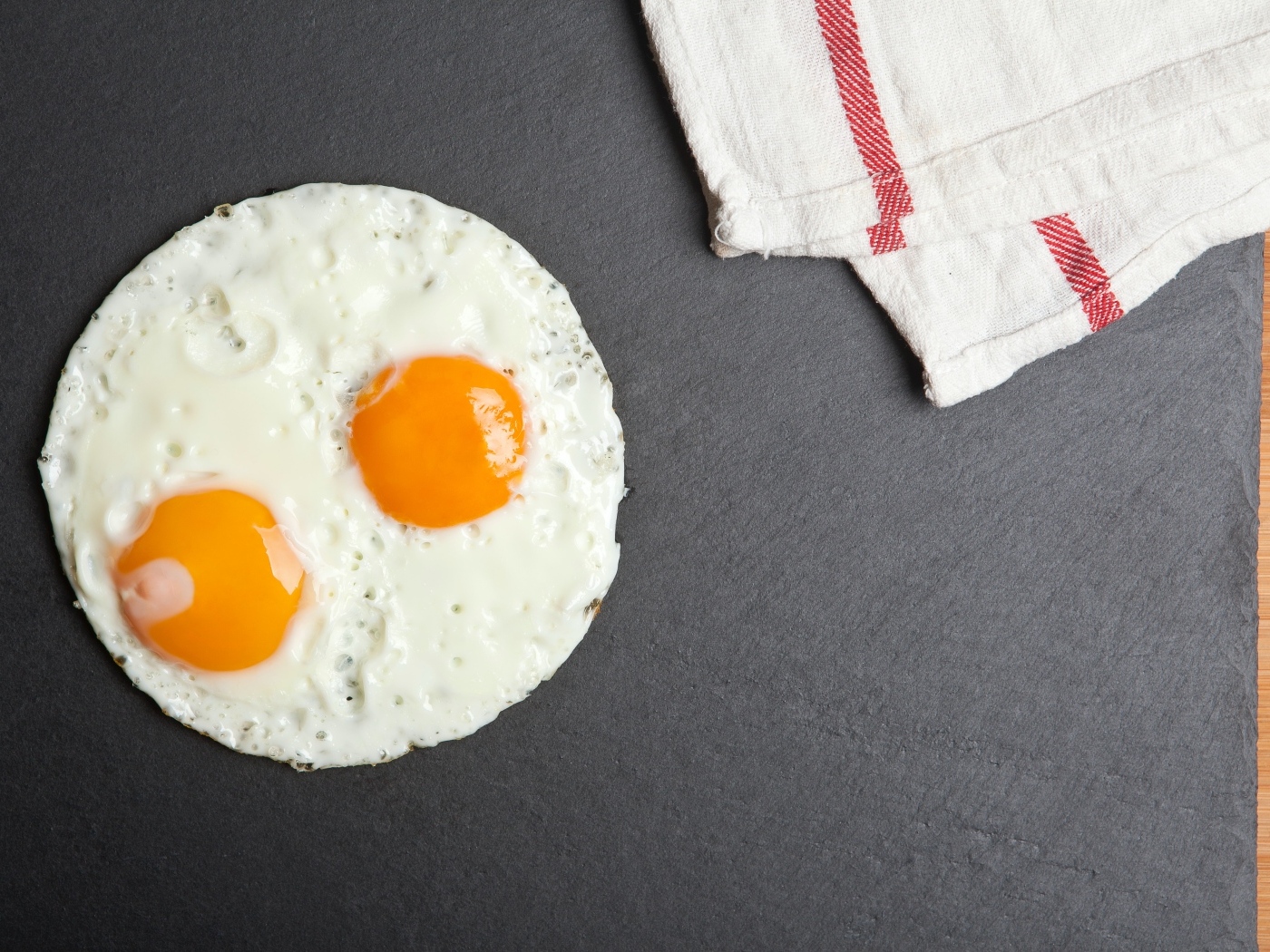 Яичница глазунья на сером столе с полотенцем