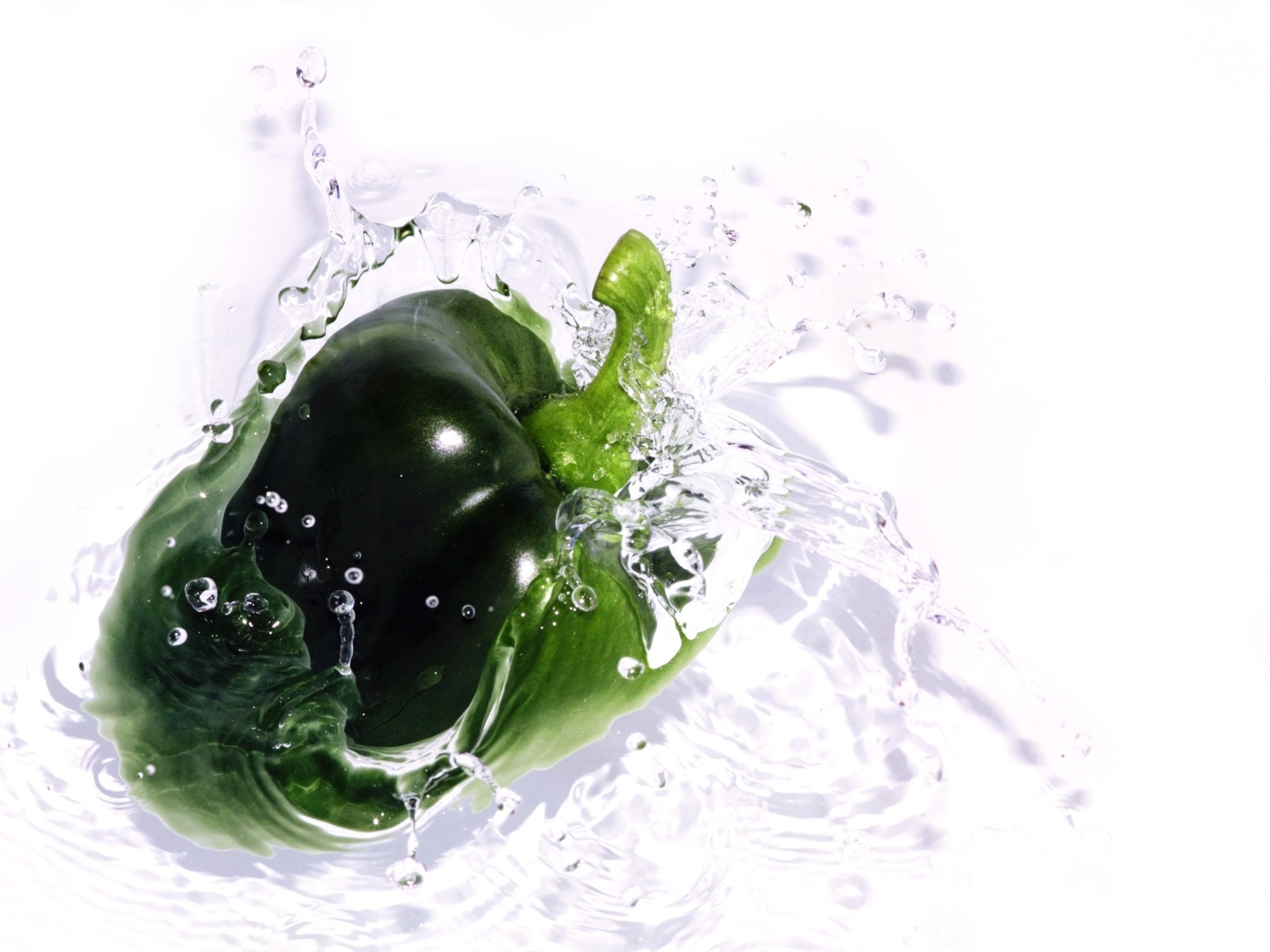 Зеленый перец в воде на белом фоне