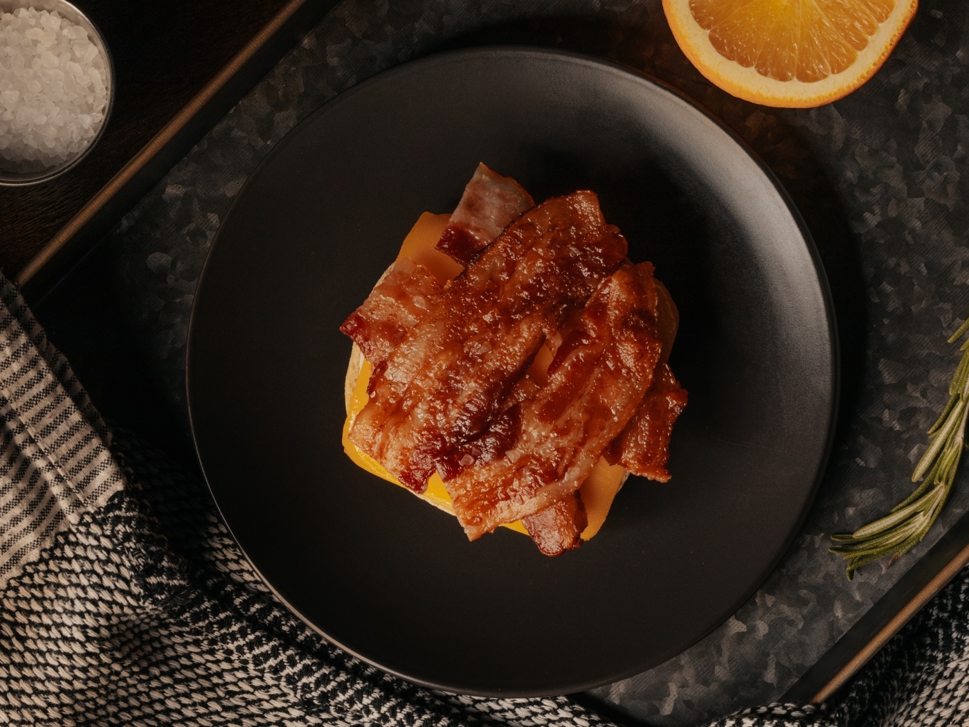 Бутерброд с сыром и жареным беконом на тарелке