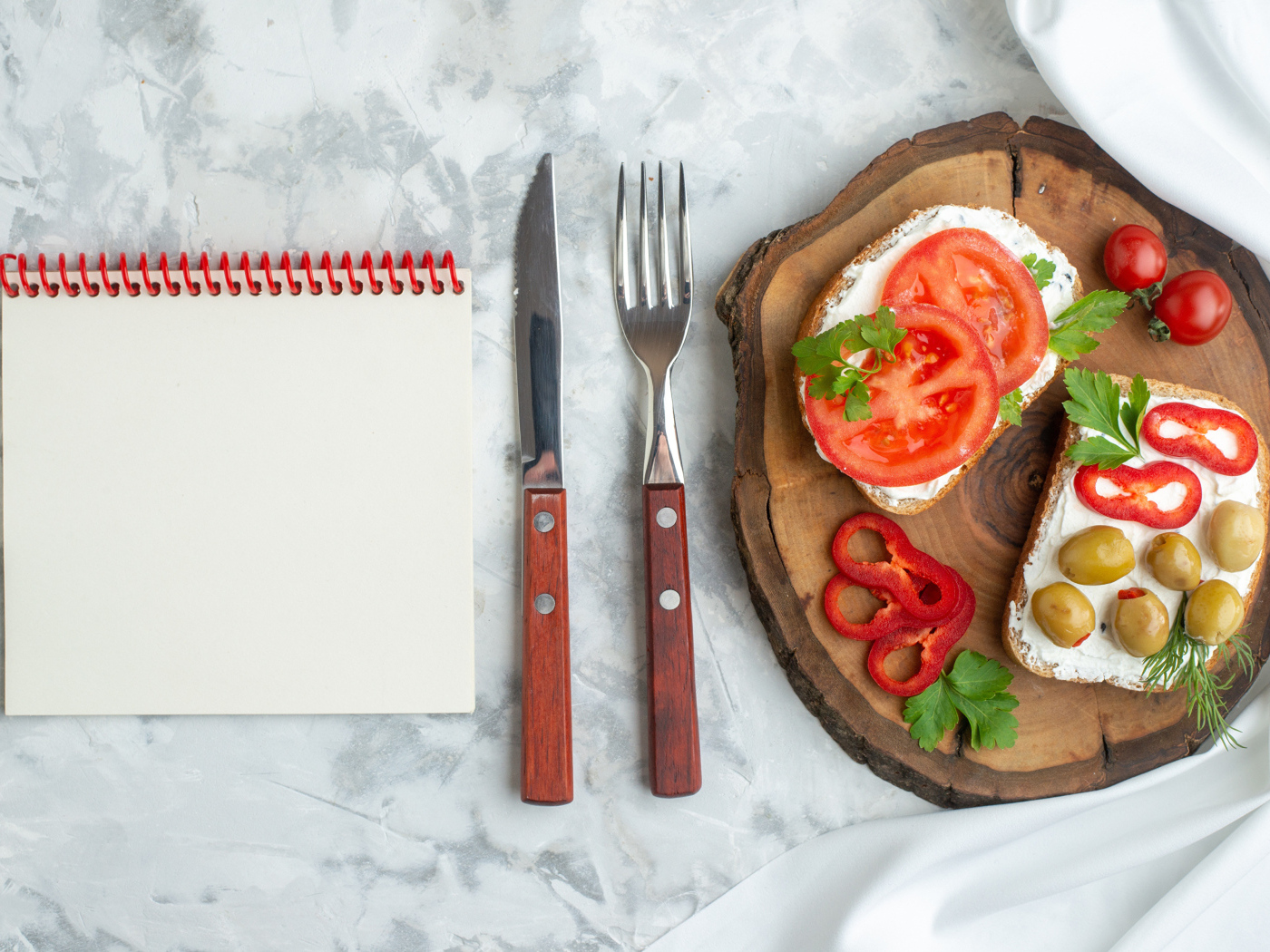 Бутерброды на столе со столовыми приборами и блокнотом