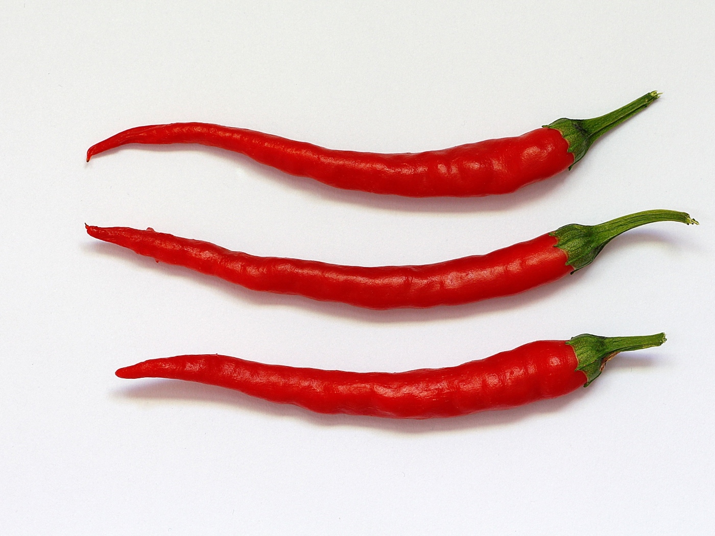Три перца чили на сером фоне