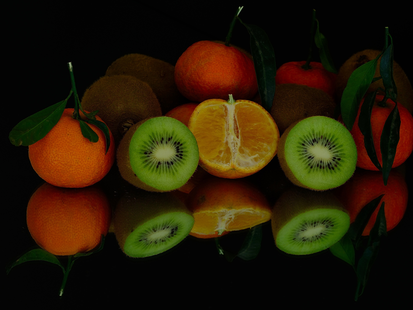 Цитрусовые фрукты на черной зеркальной поверхности