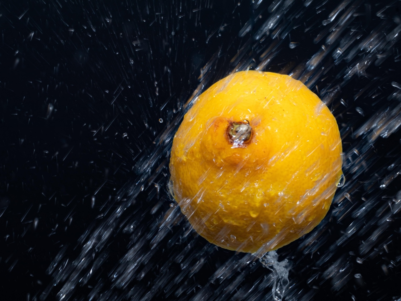 Лимон в брызгах воды на черном фоне