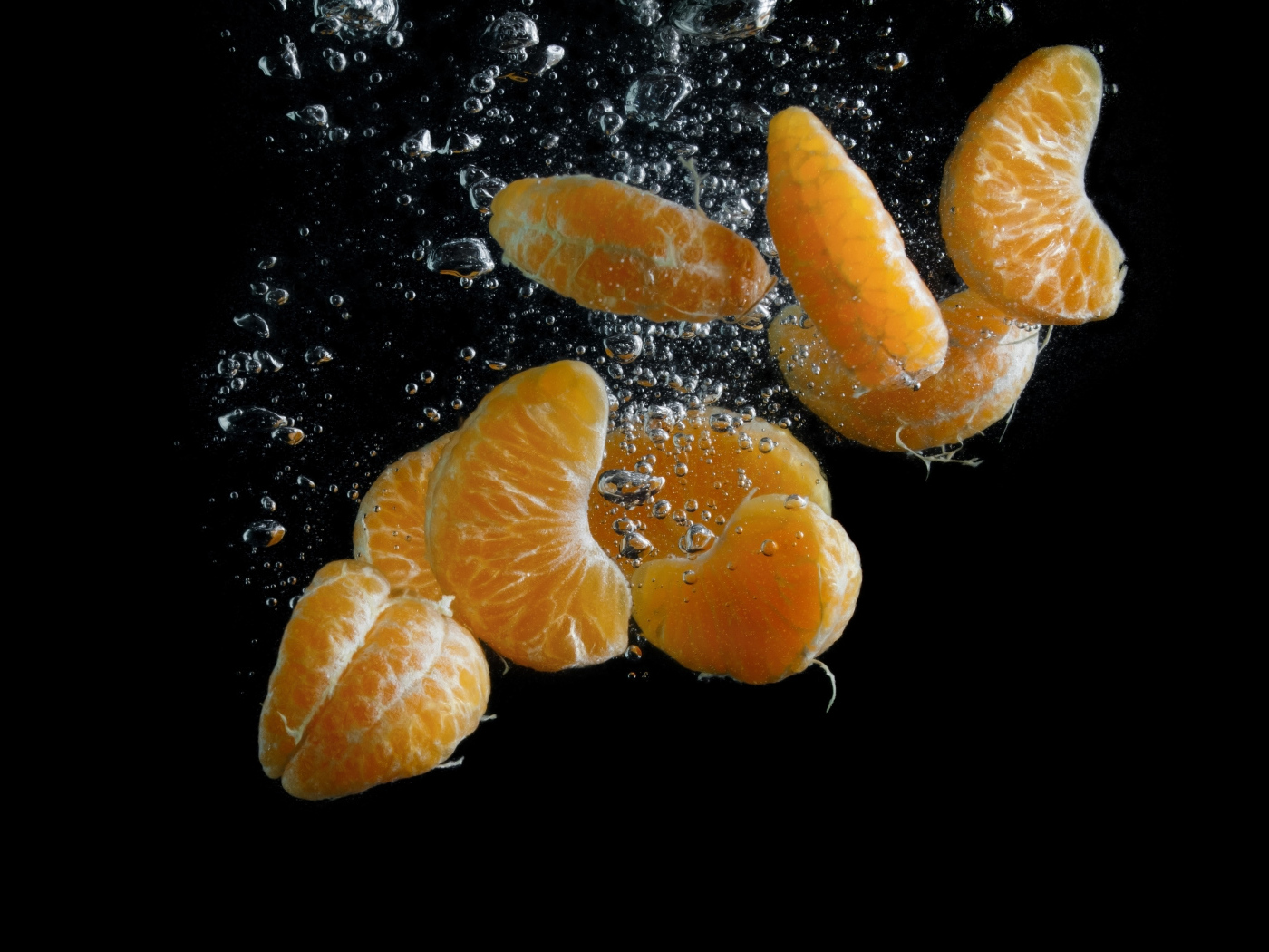 Дольки мандарина в воде на черном фоне