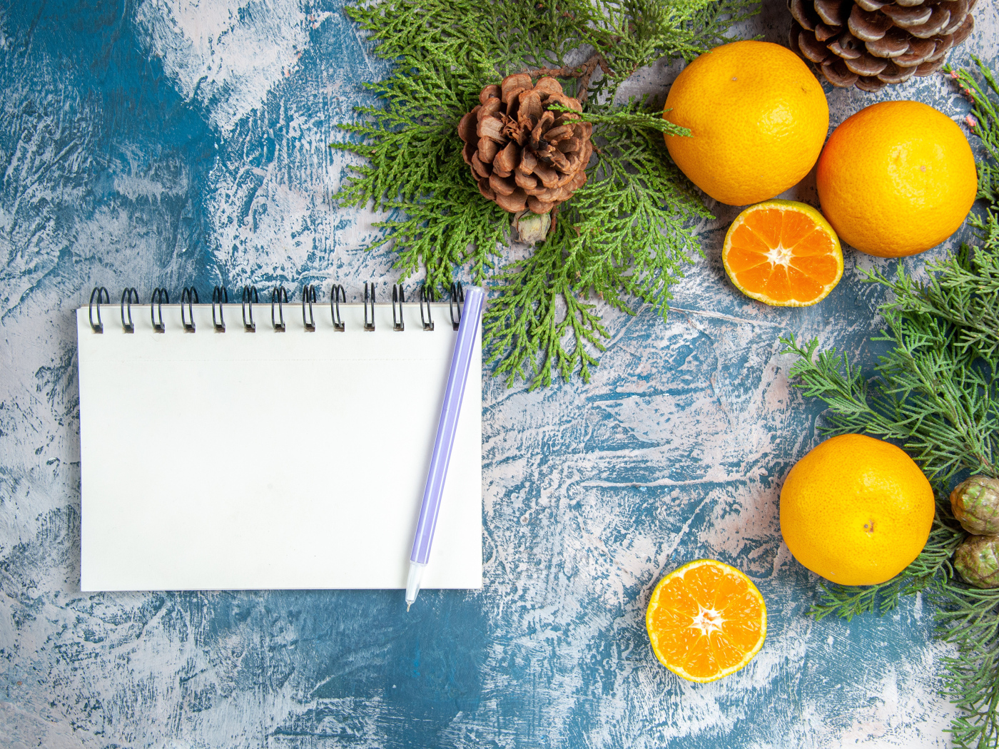 Блокнот на столе с мандаринами и ветками