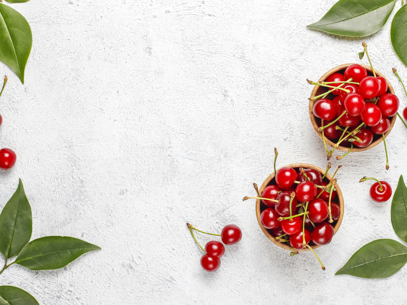 Спелая красная вишня с зелеными листьями на столе