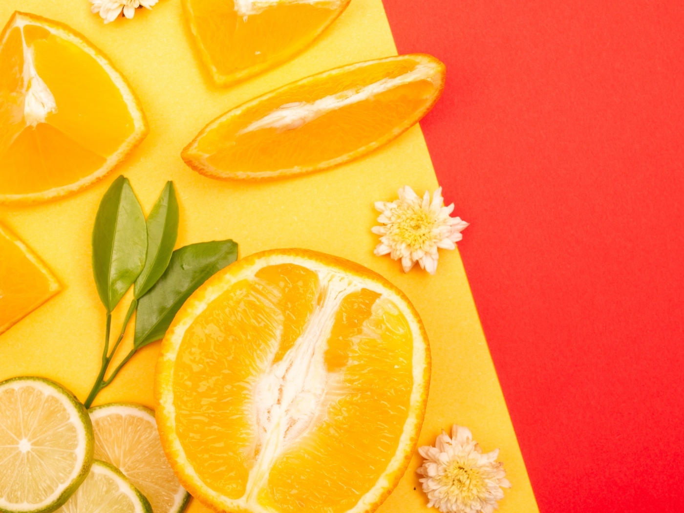 Кусочки апельсина и лайма на разноцветной поверхности 