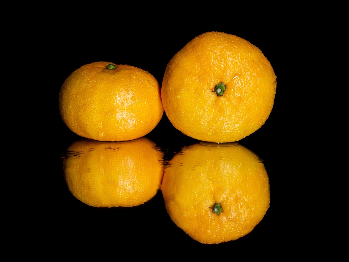 Два мандарина на черной зеркальной поверхности 