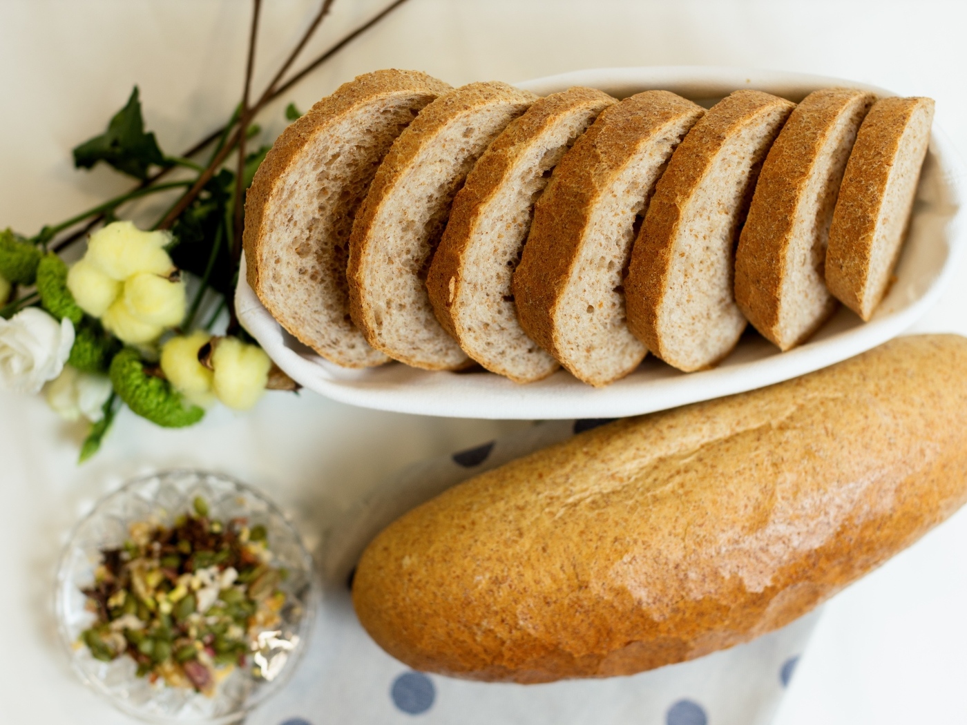 Батон нарезанный на столе с цветами